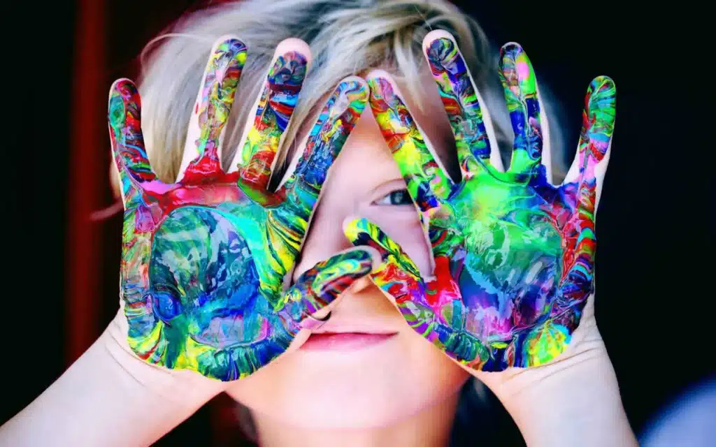 Imagen de una niña enseñando sus manos pintadas de multiples colores. Psicólogos de Costa Rica